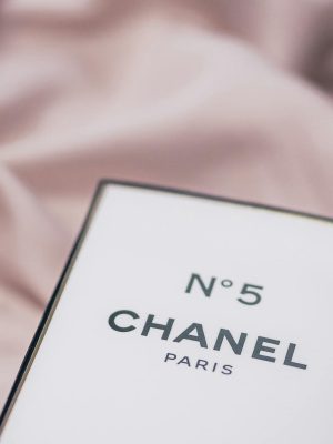 Elegant Chanel No. 5 perfume box placed on a delicate fabric surface.