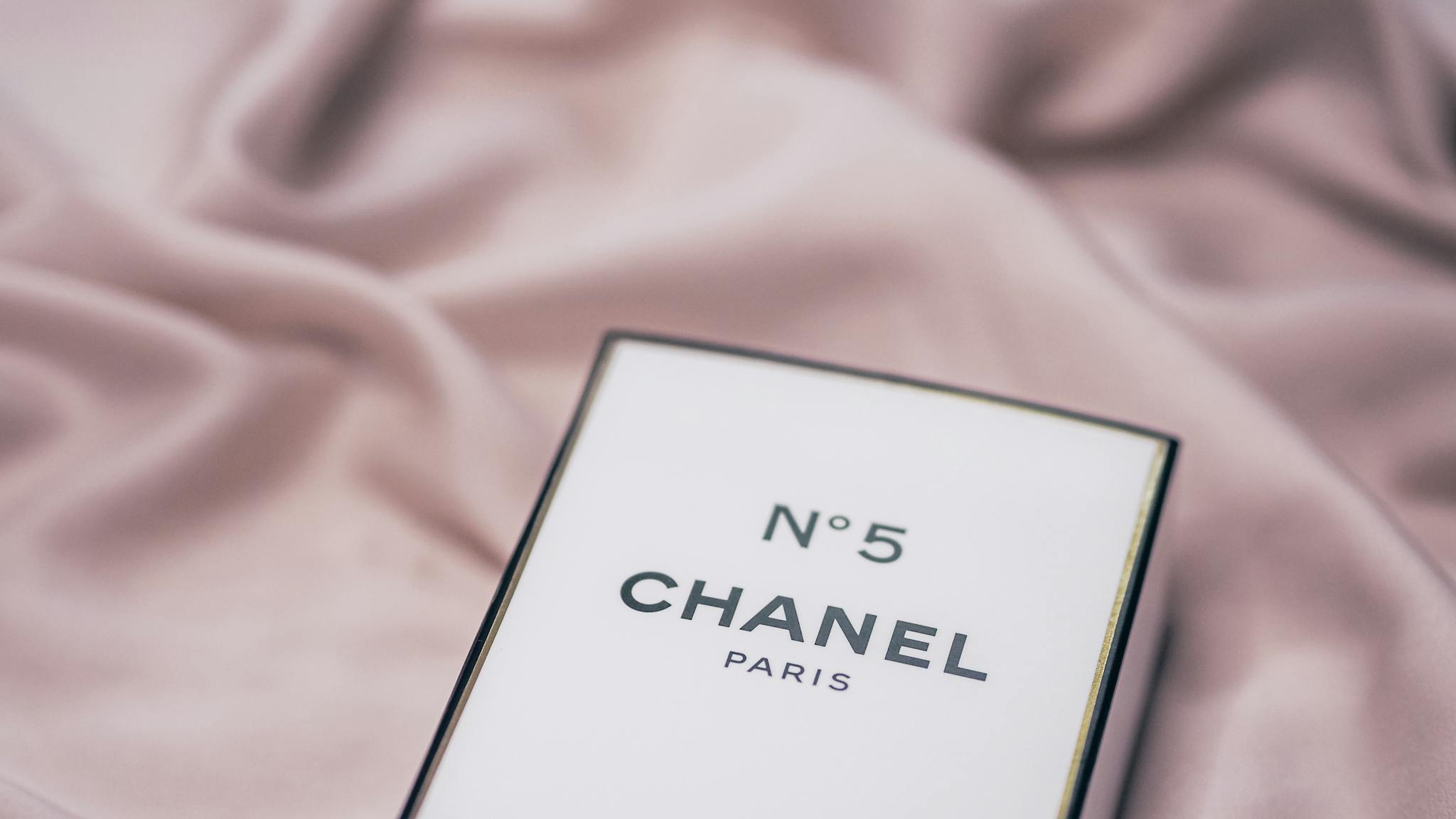 Elegant Chanel No. 5 perfume box placed on a delicate fabric surface.