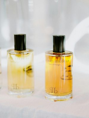 Two stylish glass perfume bottles with black caps on a bright background.